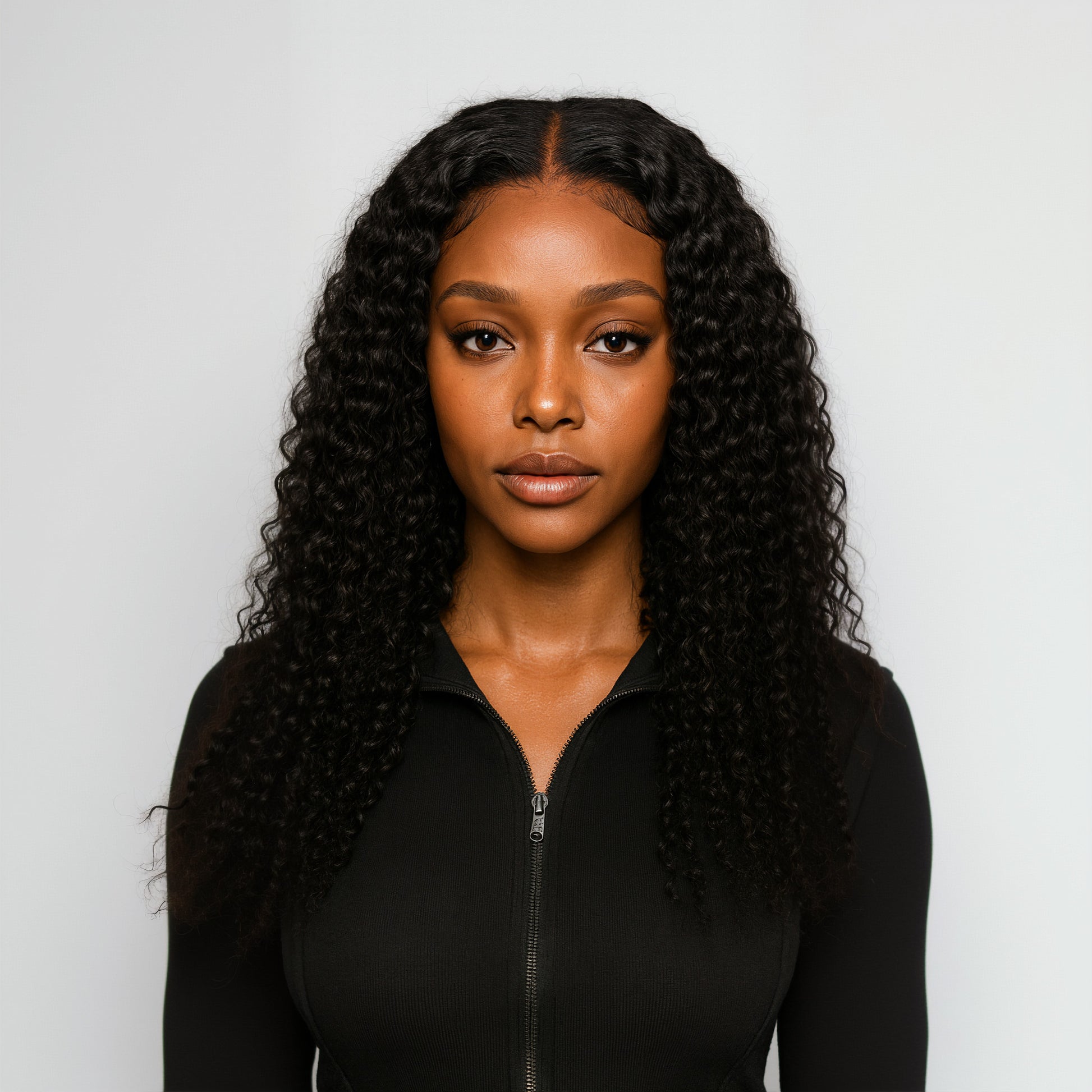 Woman with long, curly black hair wearing a black top against a light gray background
